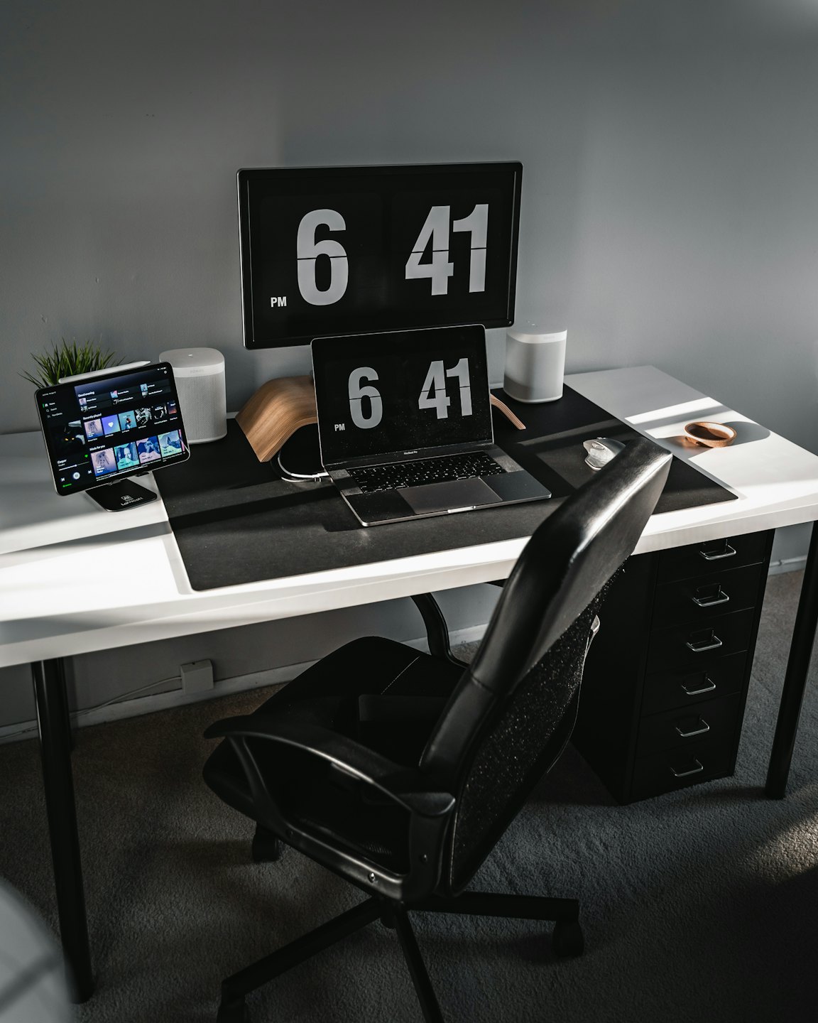 Modern home office desk with laptop, monitor, and plant.