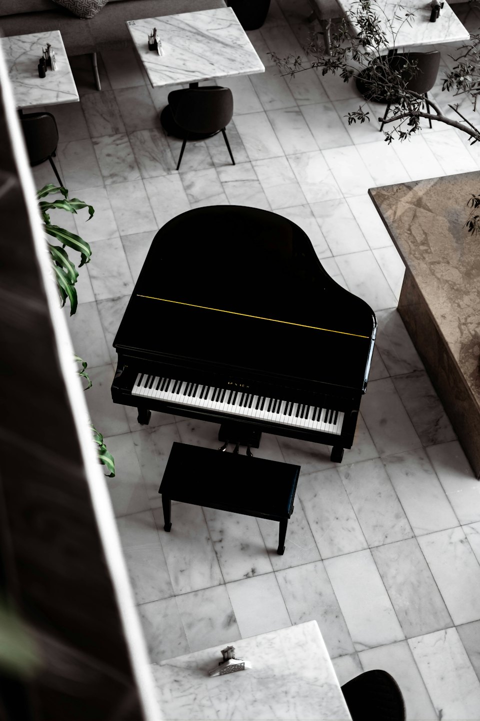 Black grand piano and bench on a marble floor.